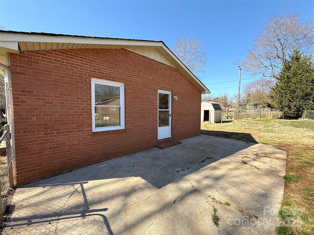 view of side of home with a yard, fence, a patio, and brick siding