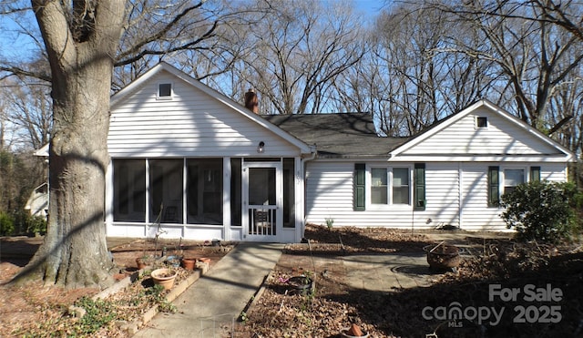 back of property with a chimney and a sunroom