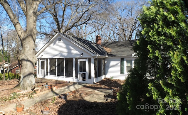 back of house with a sunroom and a chimney