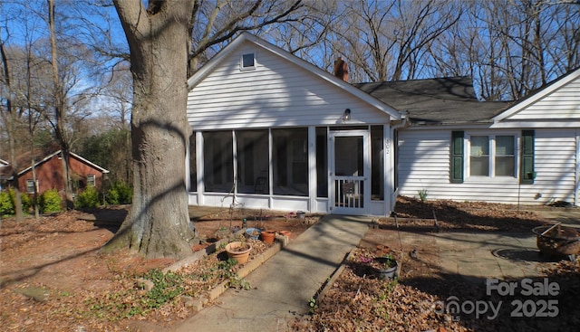 view of front of home featuring a sunroom and a chimney