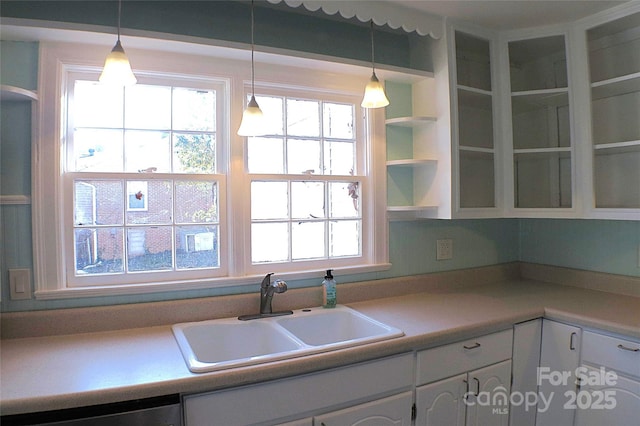 kitchen with pendant lighting, white cabinets, a sink, and dishwasher