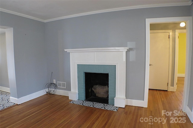 unfurnished living room with a brick fireplace, wood finished floors, visible vents, and crown molding