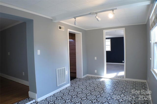 empty room featuring visible vents, crown molding, and baseboards