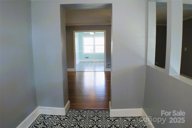 hallway with tile patterned flooring, visible vents, and baseboards