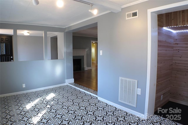 empty room with ornamental molding, visible vents, and baseboards