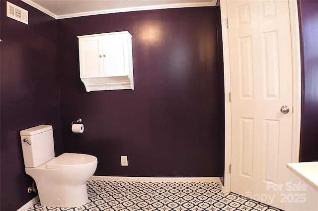 bathroom featuring toilet, baseboards, visible vents, and crown molding