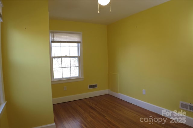 spare room with visible vents, baseboards, and wood finished floors