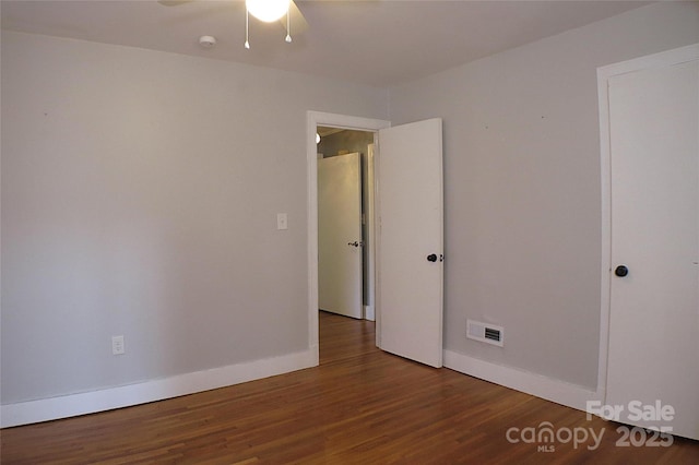 unfurnished room featuring a ceiling fan, baseboards, visible vents, and wood finished floors