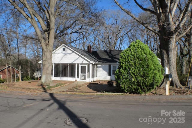 view of front of home featuring a sunroom and a chimney