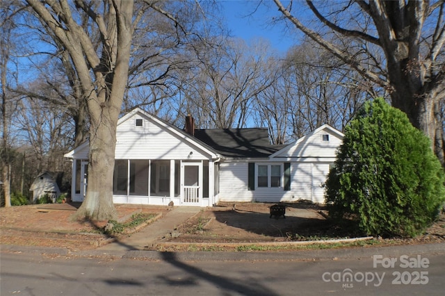 view of front of home featuring a chimney and a sunroom