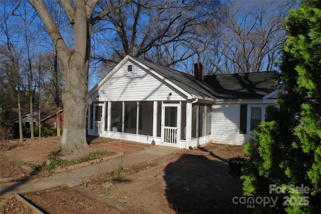 rear view of house featuring a chimney and a sunroom