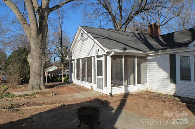 view of side of home featuring a sunroom and a chimney