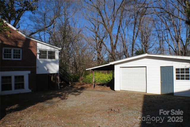 exterior space with dirt driveway and a detached garage