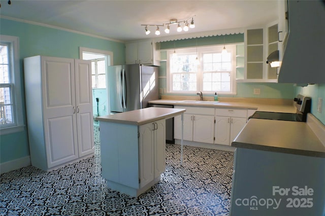 kitchen with light tile patterned floors, appliances with stainless steel finishes, a center island, crown molding, and a sink