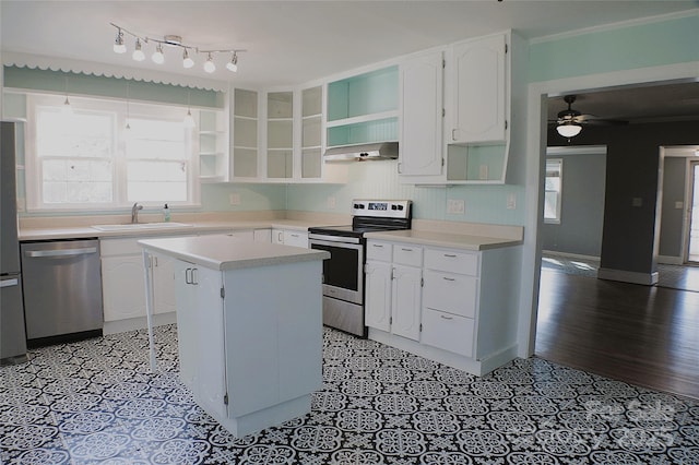 kitchen with under cabinet range hood, stainless steel appliances, a sink, white cabinetry, and open shelves