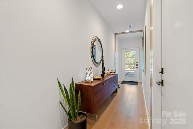 corridor featuring light wood finished floors, visible vents, and recessed lighting