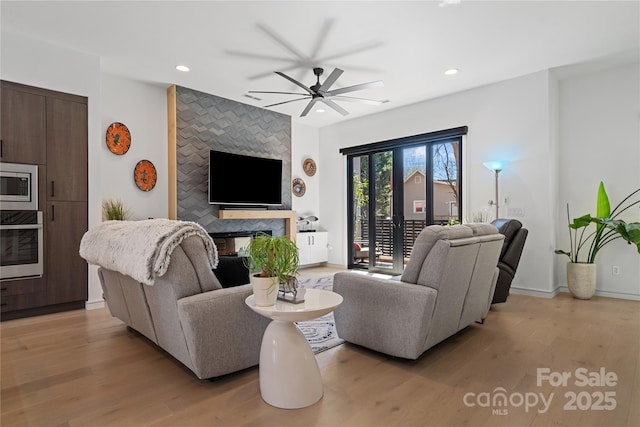 living area with light wood finished floors, recessed lighting, a high end fireplace, ceiling fan, and baseboards