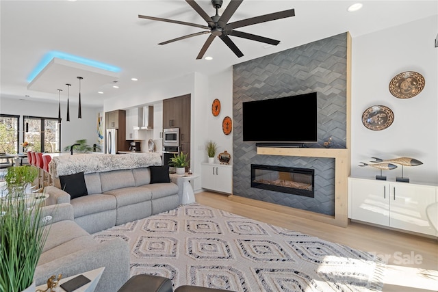 living room with recessed lighting, a fireplace, light wood-style flooring, and ceiling fan