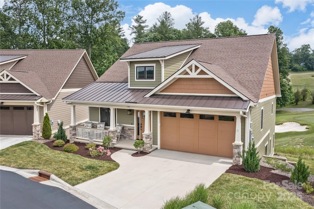 craftsman-style house featuring a porch, an attached garage, concrete driveway, stone siding, and a standing seam roof