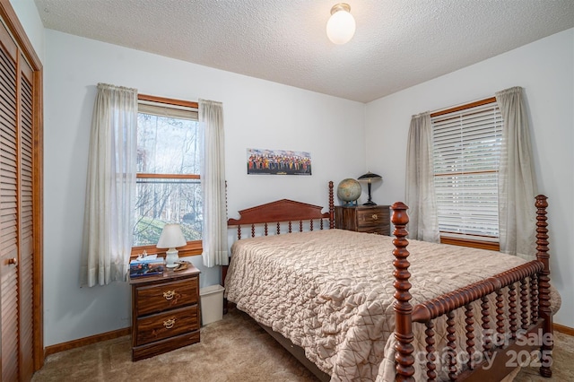 bedroom featuring a closet, light colored carpet, a textured ceiling, and baseboards