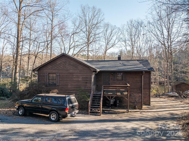 chalet / cabin featuring a wooden deck, a chimney, stairway, and brick siding