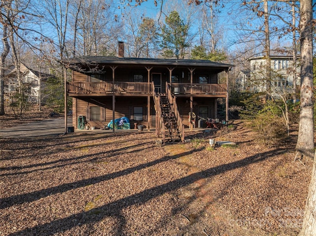 back of property with a chimney, a wooden deck, and stairs