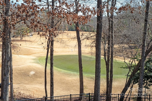 view of home's community featuring view of golf course and fence