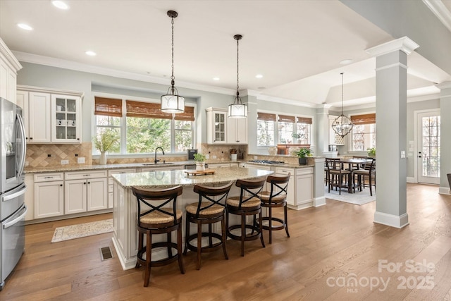 kitchen with white cabinetry, a kitchen island, glass insert cabinets, and a sink