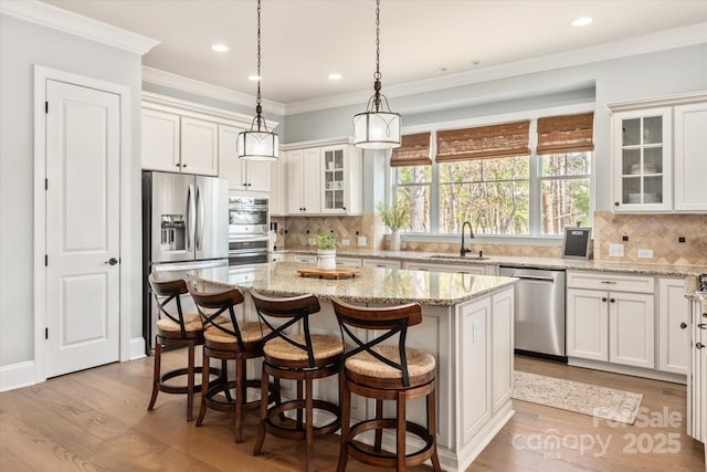 kitchen with glass insert cabinets, a kitchen island, appliances with stainless steel finishes, and a sink