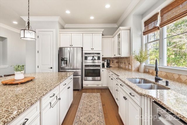 kitchen featuring stainless steel appliances, a sink, white cabinetry, light stone countertops, and pendant lighting