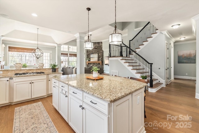 kitchen featuring a kitchen island, stainless steel gas stovetop, white cabinetry, and hanging light fixtures