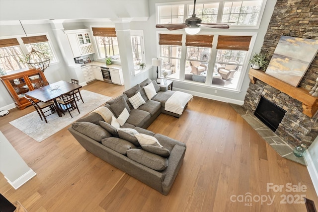 living area with a wealth of natural light, a stone fireplace, and light wood finished floors