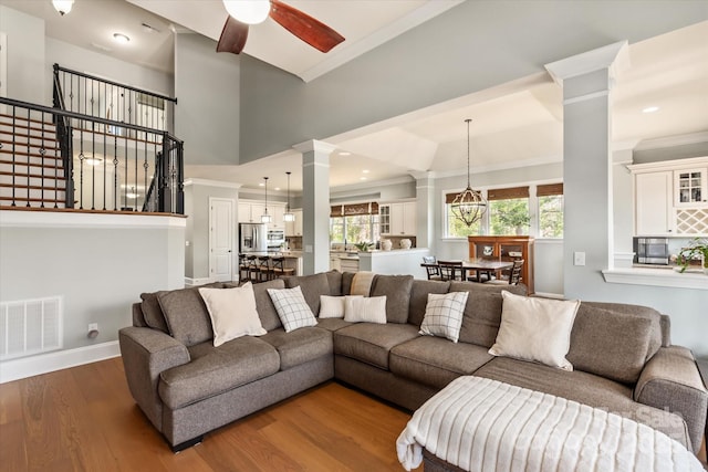 living room featuring a healthy amount of sunlight, wood finished floors, visible vents, and ornate columns