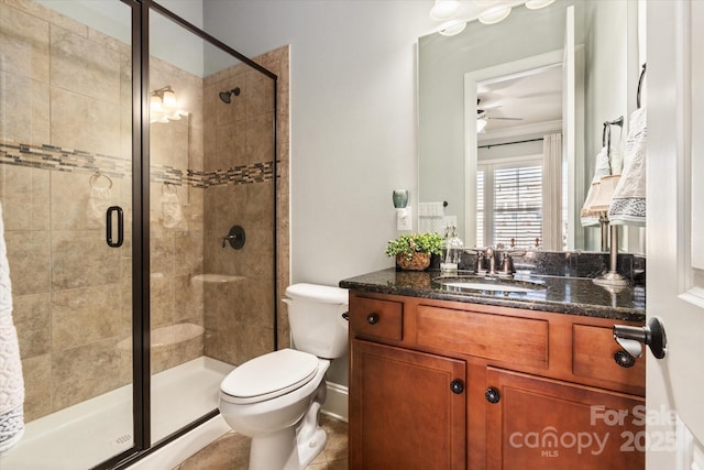 bathroom featuring a stall shower, vanity, toilet, and a ceiling fan