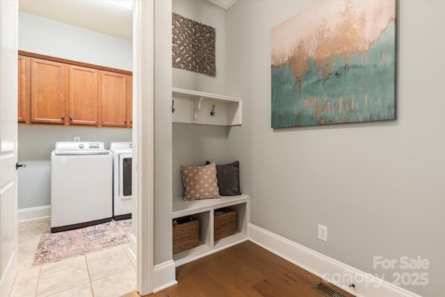 laundry area featuring cabinet space, washing machine and dryer, visible vents, and baseboards