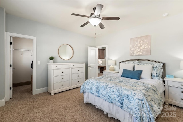 bedroom with a walk in closet, a closet, light carpet, ceiling fan, and baseboards