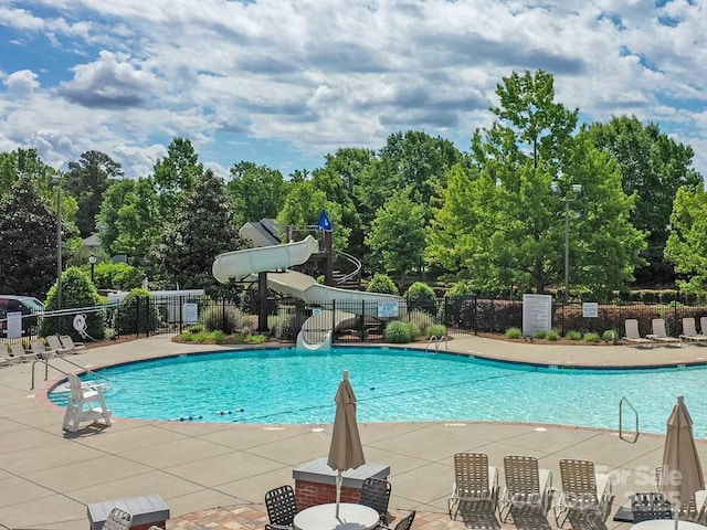 view of pool featuring a water slide and fence