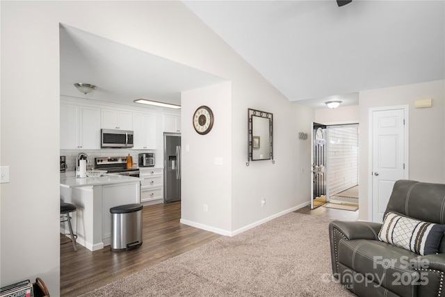 living area featuring vaulted ceiling, dark carpet, dark wood-style floors, and baseboards