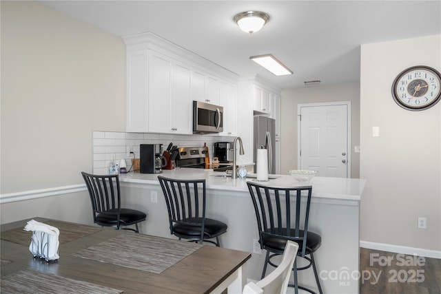 kitchen featuring a peninsula, appliances with stainless steel finishes, a breakfast bar area, and white cabinets