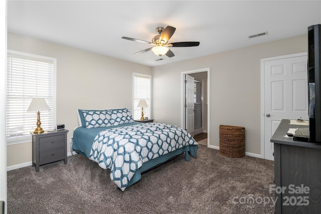 bedroom featuring baseboards, visible vents, a ceiling fan, ensuite bath, and dark colored carpet