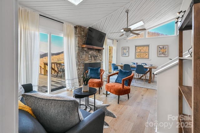 sitting room with ceiling fan, a fireplace, a wealth of natural light, and light wood-style floors