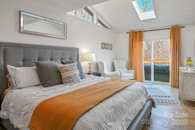 bedroom featuring lofted ceiling with skylight, access to outside, and wood finished floors