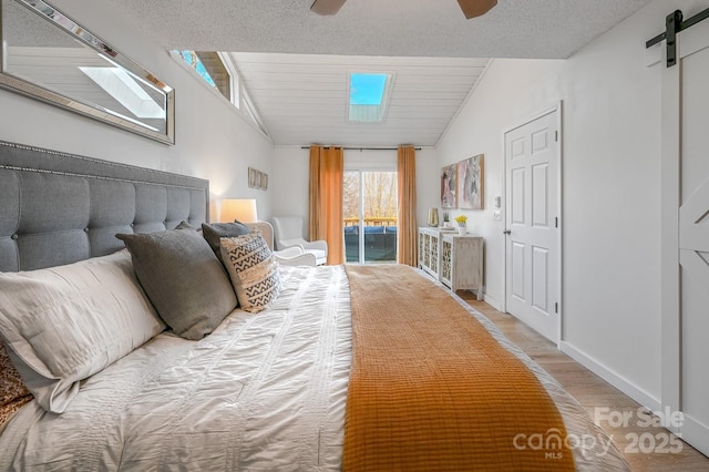 bedroom featuring a barn door, lofted ceiling, ceiling fan, wood finished floors, and access to outside