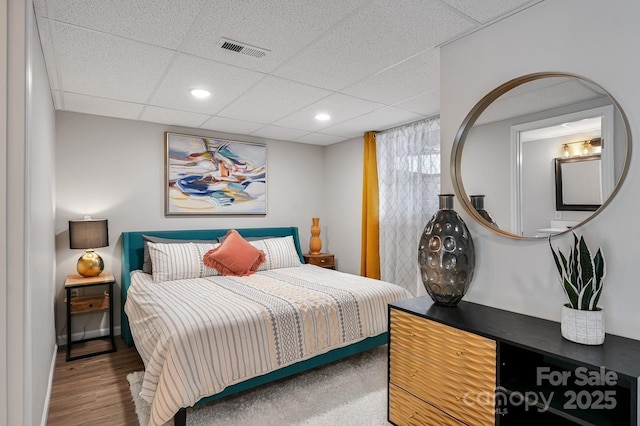 bedroom featuring baseboards, visible vents, a drop ceiling, wood finished floors, and recessed lighting