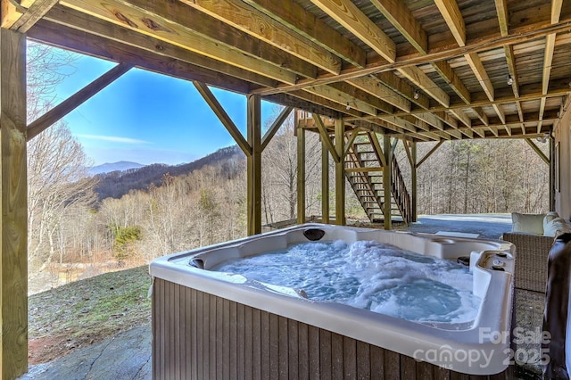 view of patio / terrace featuring a forest view, a hot tub, stairs, and a mountain view