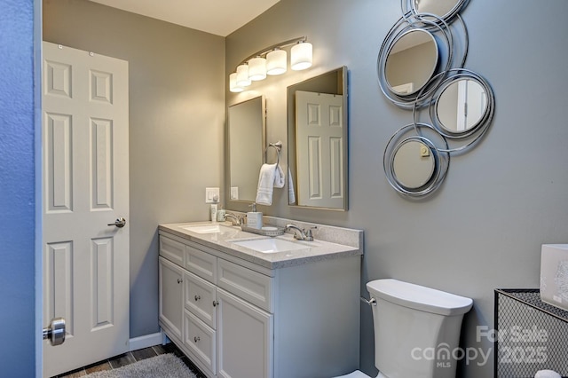 bathroom with toilet, double vanity, and a sink