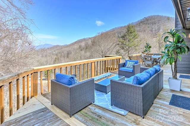 deck with a mountain view, outdoor dining area, and an outdoor living space