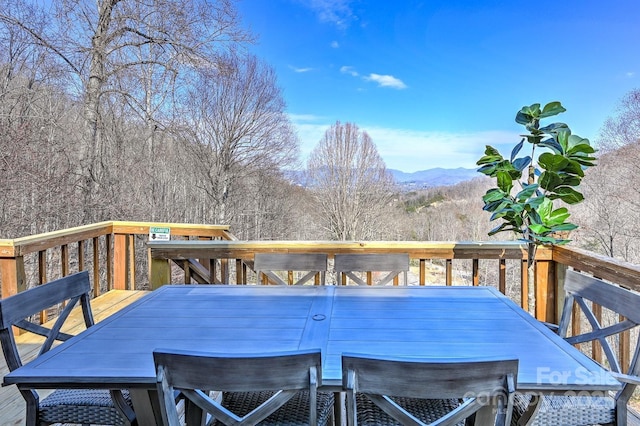 wooden terrace with outdoor dining area and a mountain view