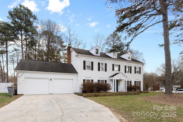 view of front of home featuring a front yard, concrete driveway, a chimney, and an attached garage