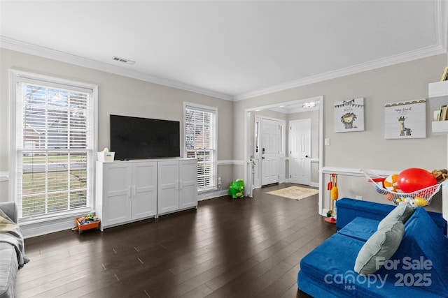 living room with crown molding, hardwood / wood-style floors, visible vents, and a healthy amount of sunlight